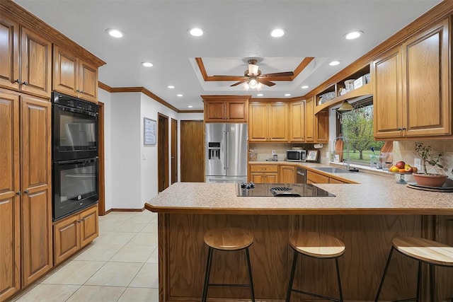 kitchen featuring a peninsula, a raised ceiling, baseboards, black appliances, and ornamental molding