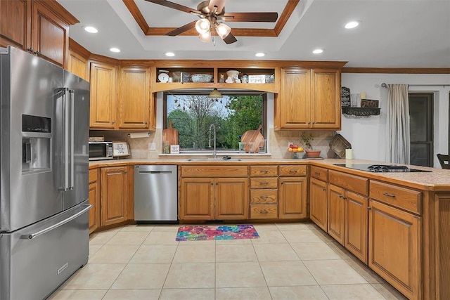 kitchen featuring stainless steel appliances, light countertops, a peninsula, ornamental molding, and a raised ceiling