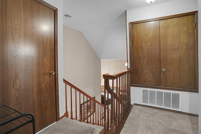 staircase with vaulted ceiling, visible vents, and carpet flooring