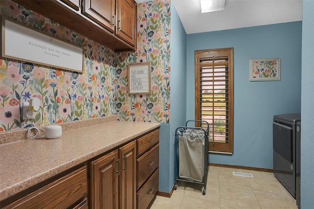 kitchen with brown cabinetry, visible vents, baseboards, and separate washer and dryer