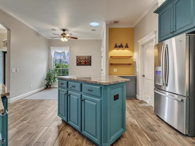 2809 Morgan Trace Rd, Yukon, OK 73099 - kitchen featuring stainless steel fridge, a center island, blue cabinetry, arched walkways, and ornamental molding