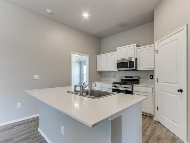 kitchen featuring backsplash, a sink, stainless steel appliances, and white cabinetry