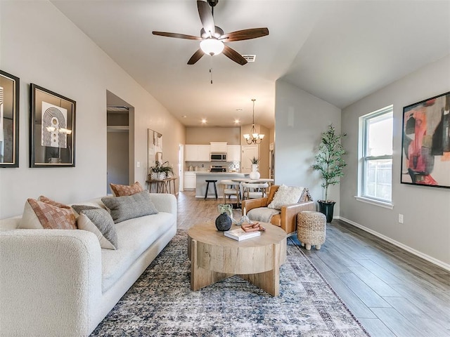3721 Central Park Dr, Moore, OK 73160 - living room with lofted ceiling, light wood-style floors, a ceiling fan, a chandelier, and baseboards
