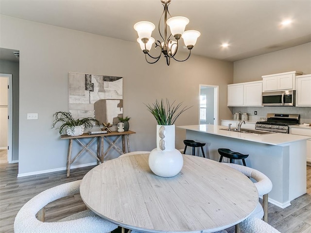 3721 Central Park Dr, Moore, OK 73160 - dining room featuring light wood-type flooring, a chandelier, and baseboards