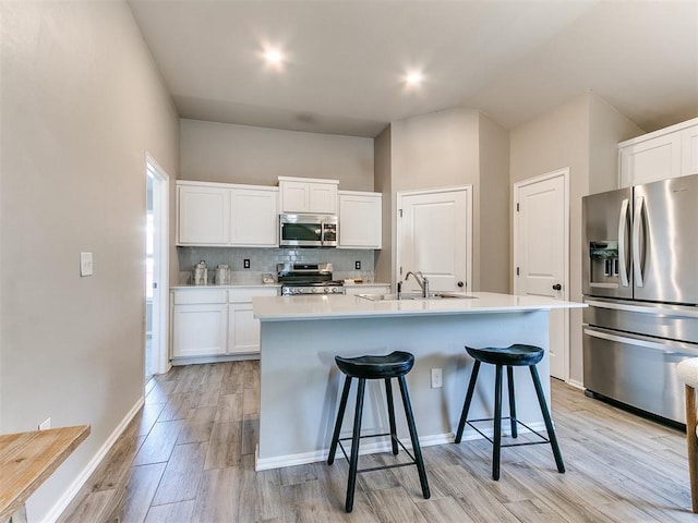 3721 Central Park Dr, Moore, OK 73160 - kitchen with stainless steel appliances, a sink, light wood-style flooring, white cabinets, and vaulted ceiling