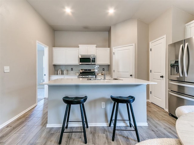 3721 Central Park Dr, Moore, OK 73160 - kitchen with appliances with stainless steel finishes, decorative backsplash, a breakfast bar, white cabinets, and a center island with sink
