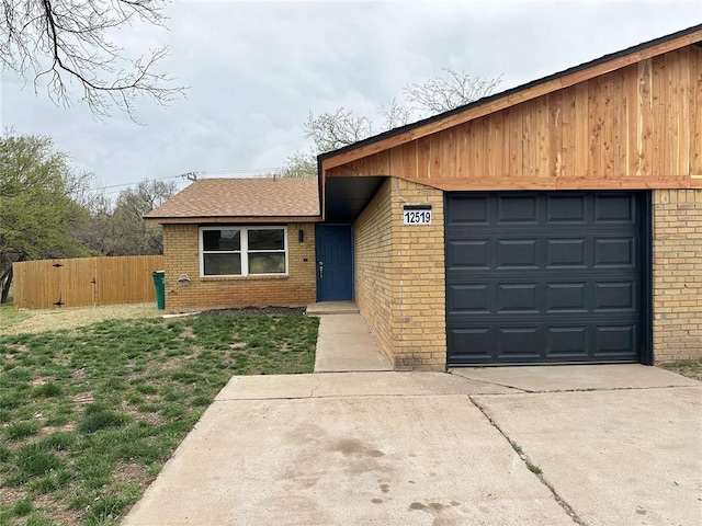 view of front of home featuring driveway, fence, and brick siding