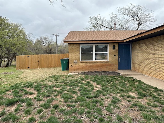 exterior space with a lawn, fence, and brick siding