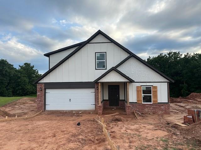 11767 Sweeping Ln, Guthrie, OK 73044 - view of front of home featuring board and batten siding, brick siding, an attached garage, and dirt driveway