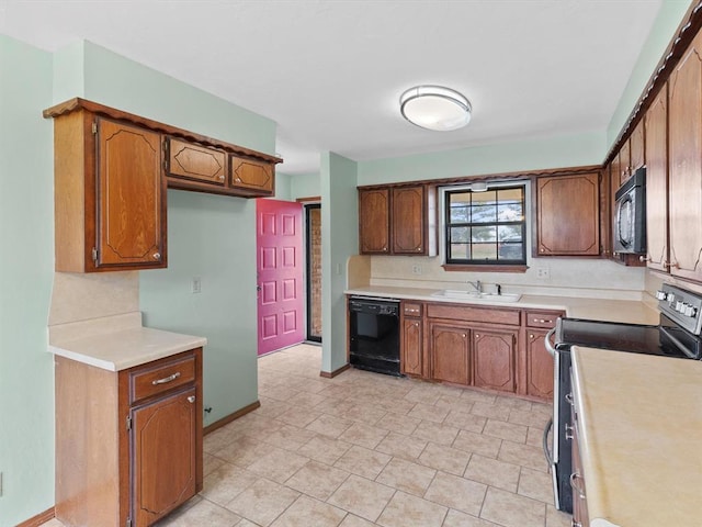 kitchen featuring light countertops, a sink, black appliances, and brown cabinets