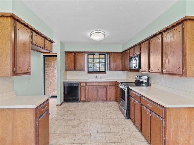 kitchen featuring light countertops, a sink, black appliances, and brown cabinets