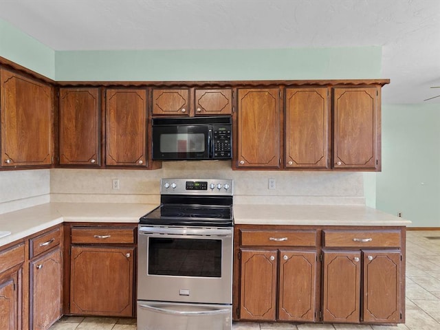 kitchen featuring light countertops, black microwave, stainless steel range with electric cooktop, and brown cabinets