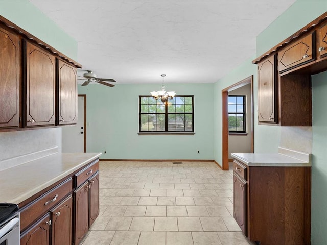 kitchen with light countertops, ceiling fan with notable chandelier, baseboards, and pendant lighting