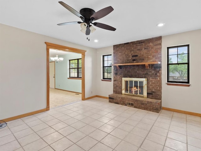 unfurnished living room featuring ceiling fan with notable chandelier, baseboards, a fireplace, and visible vents