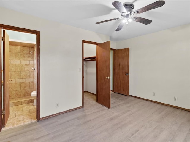 unfurnished bedroom with a closet, baseboards, light wood-style floors, ensuite bath, and a spacious closet