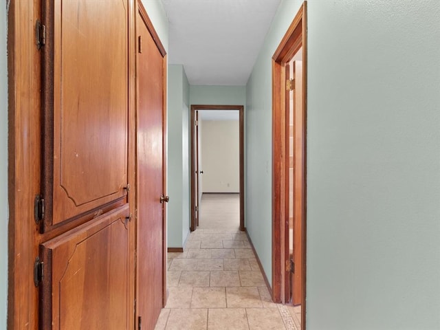 corridor with baseboards and light tile patterned floors