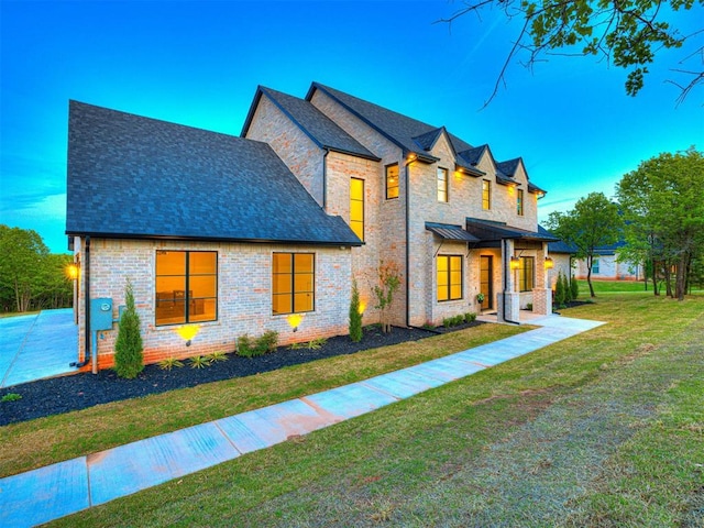 view of front of house with brick siding, roof with shingles, and a front lawn