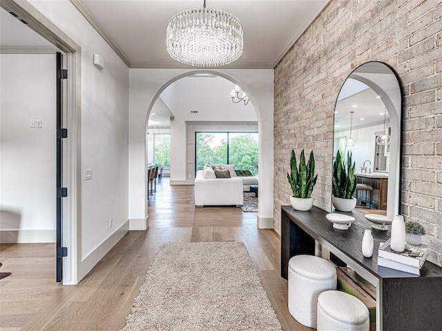 interior space with a chandelier, wood finished floors, baseboards, and ornamental molding