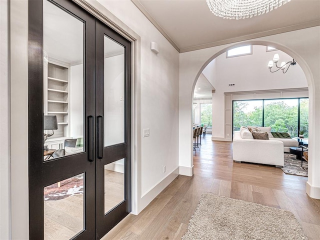 foyer entrance featuring a chandelier, light wood-style flooring, a healthy amount of sunlight, and arched walkways