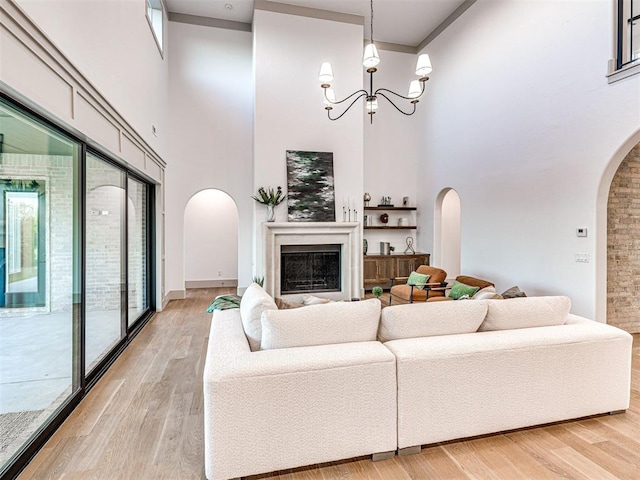 living area featuring arched walkways, light wood-style floors, a high ceiling, and a fireplace