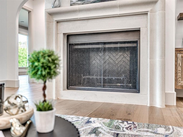 room details featuring a fireplace, wood finished floors, and arched walkways