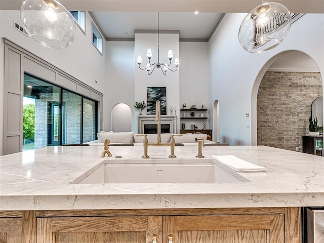 kitchen featuring open floor plan, visible vents, an inviting chandelier, a towering ceiling, and light stone countertops