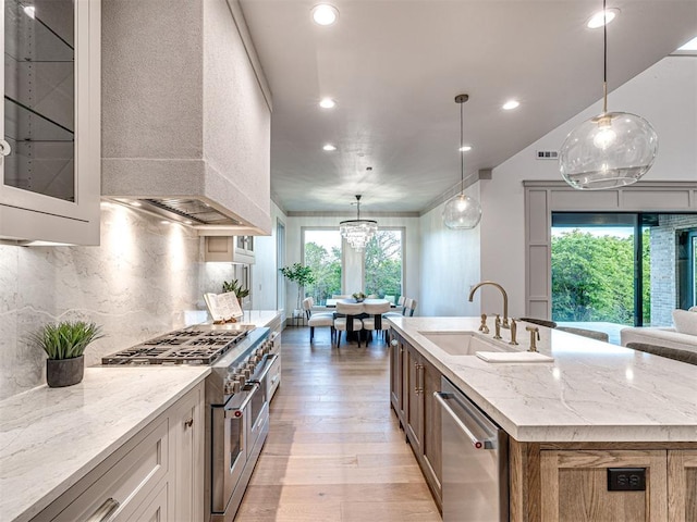 kitchen featuring a sink, plenty of natural light, light wood-style floors, custom range hood, and appliances with stainless steel finishes