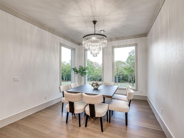 dining area featuring plenty of natural light, wood finished floors, and an inviting chandelier