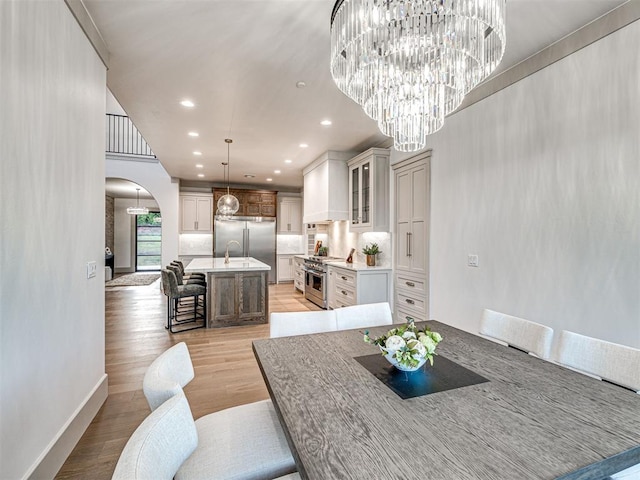 dining area featuring recessed lighting, arched walkways, light wood-type flooring, baseboards, and a chandelier