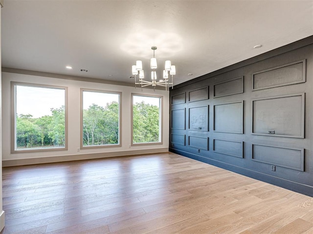 unfurnished dining area featuring a healthy amount of sunlight, wood finished floors, and a chandelier