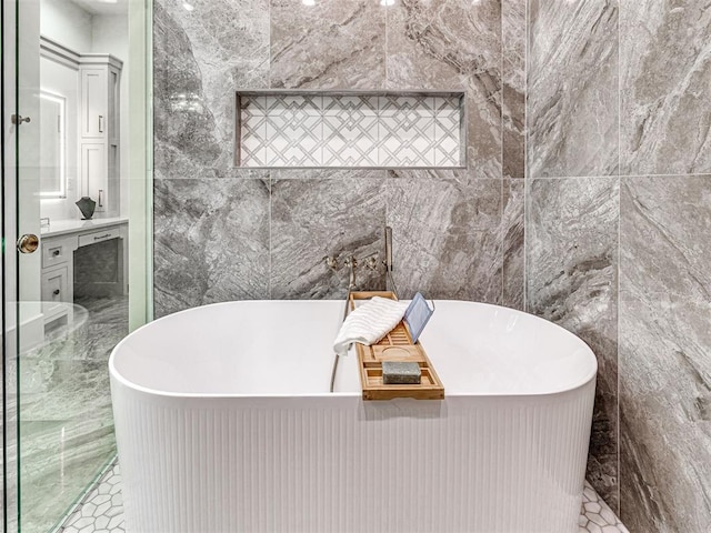 bathroom with vanity, a soaking tub, and tile walls