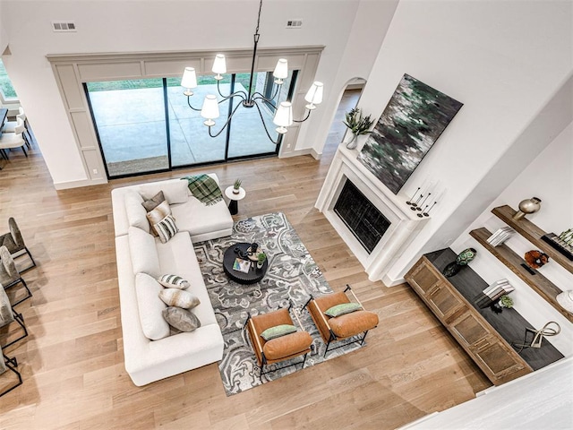 living area with a towering ceiling, a chandelier, wood finished floors, and visible vents