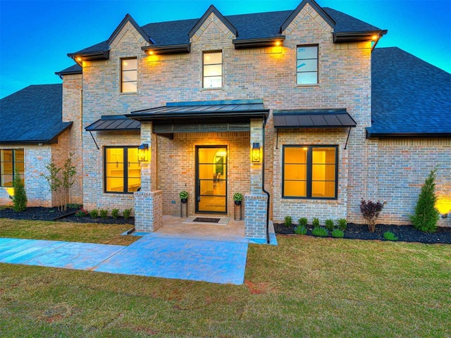 view of front facade featuring a front lawn, brick siding, a standing seam roof, and metal roof