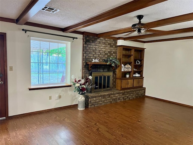 living room featuring a textured ceiling, beamed ceiling, ceiling fan, wood finished floors, and baseboards