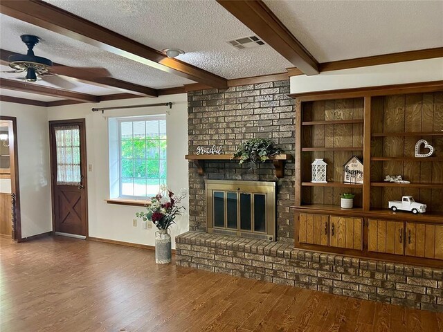 living room featuring a textured ceiling, baseboards, a ceiling fan, beamed ceiling, and wood finished floors