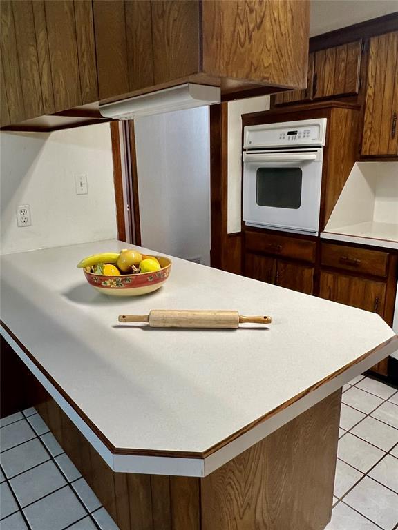 kitchen featuring oven, light tile patterned floors, light countertops, and a peninsula