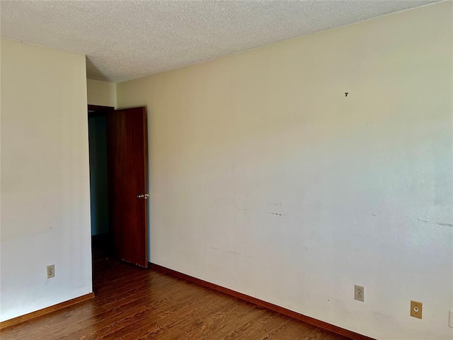 empty room with wood finished floors, baseboards, and a textured ceiling