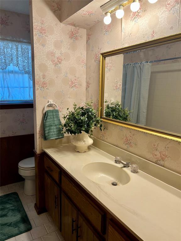 full bath with tile patterned flooring, vanity, toilet, and wallpapered walls