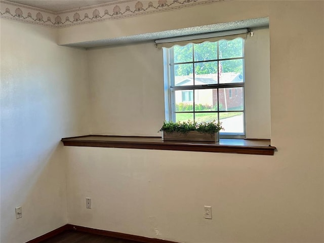spare room featuring dark wood-type flooring and baseboards