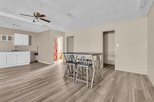 dining space with a textured ceiling, visible vents, light wood-style floors, and a ceiling fan