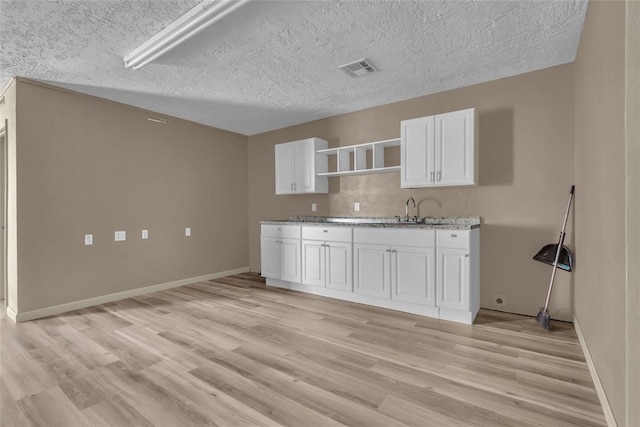 kitchen with white cabinets, light wood-style flooring, and visible vents