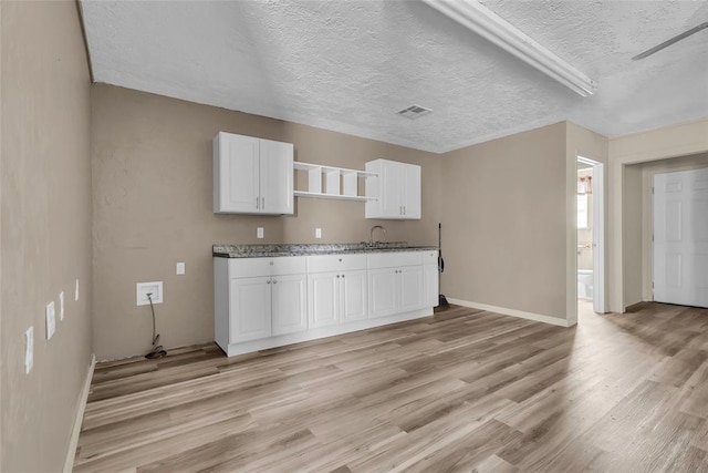 kitchen featuring white cabinetry, open shelves, light wood-type flooring, a textured ceiling, and visible vents
