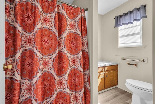 bathroom with toilet, vanity, curtained shower, and wood finished floors