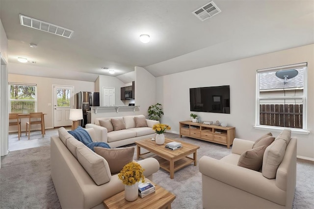 living room with baseboards, visible vents, light carpet, and vaulted ceiling
