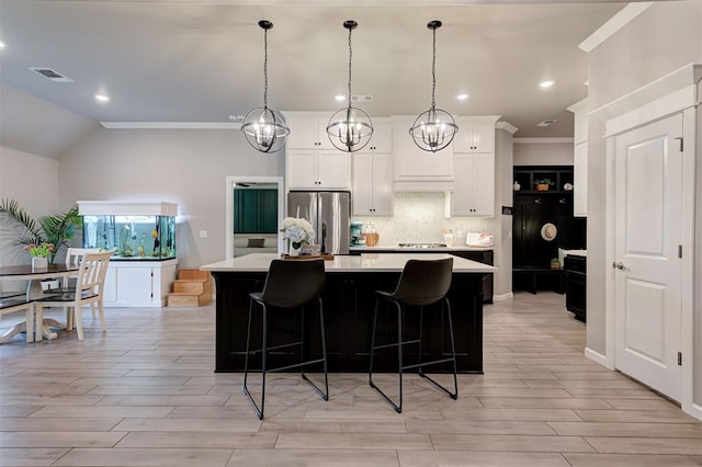 kitchen featuring a center island, light countertops, freestanding refrigerator, light wood-style floors, and decorative backsplash