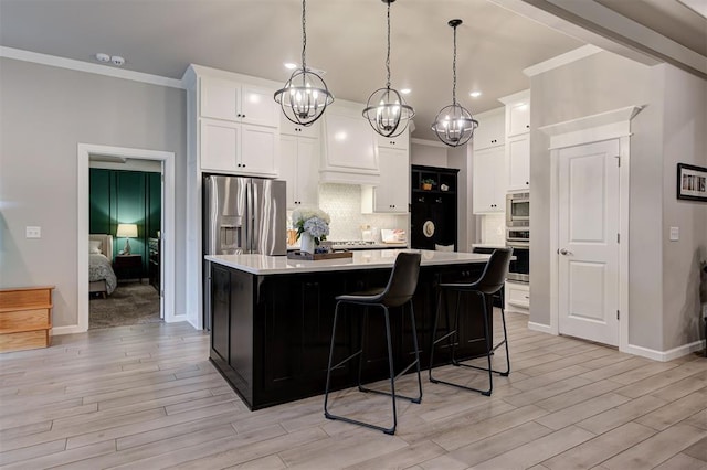 kitchen with crown molding, light wood-style floors, appliances with stainless steel finishes, light countertops, and a notable chandelier