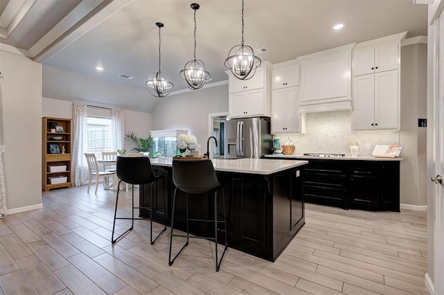 kitchen featuring stainless steel fridge, an inviting chandelier, light countertops, light wood finished floors, and decorative backsplash