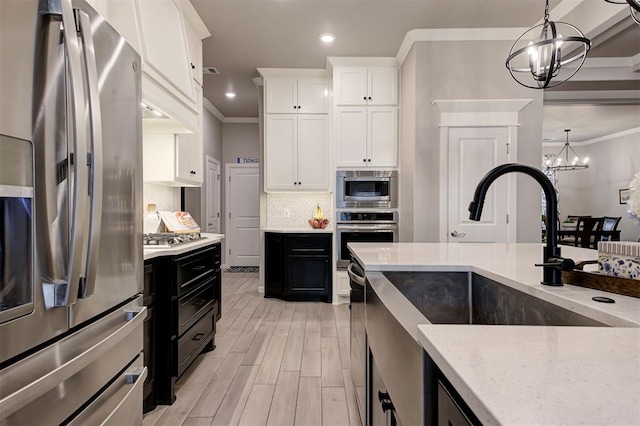 kitchen featuring dark cabinets, an inviting chandelier, recessed lighting, crown molding, and appliances with stainless steel finishes