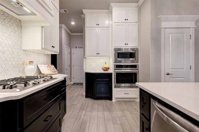 kitchen with visible vents, appliances with stainless steel finishes, light wood-type flooring, white cabinetry, and decorative backsplash