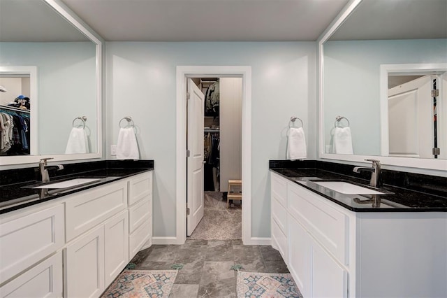 bathroom featuring a sink, two vanities, and a walk in closet